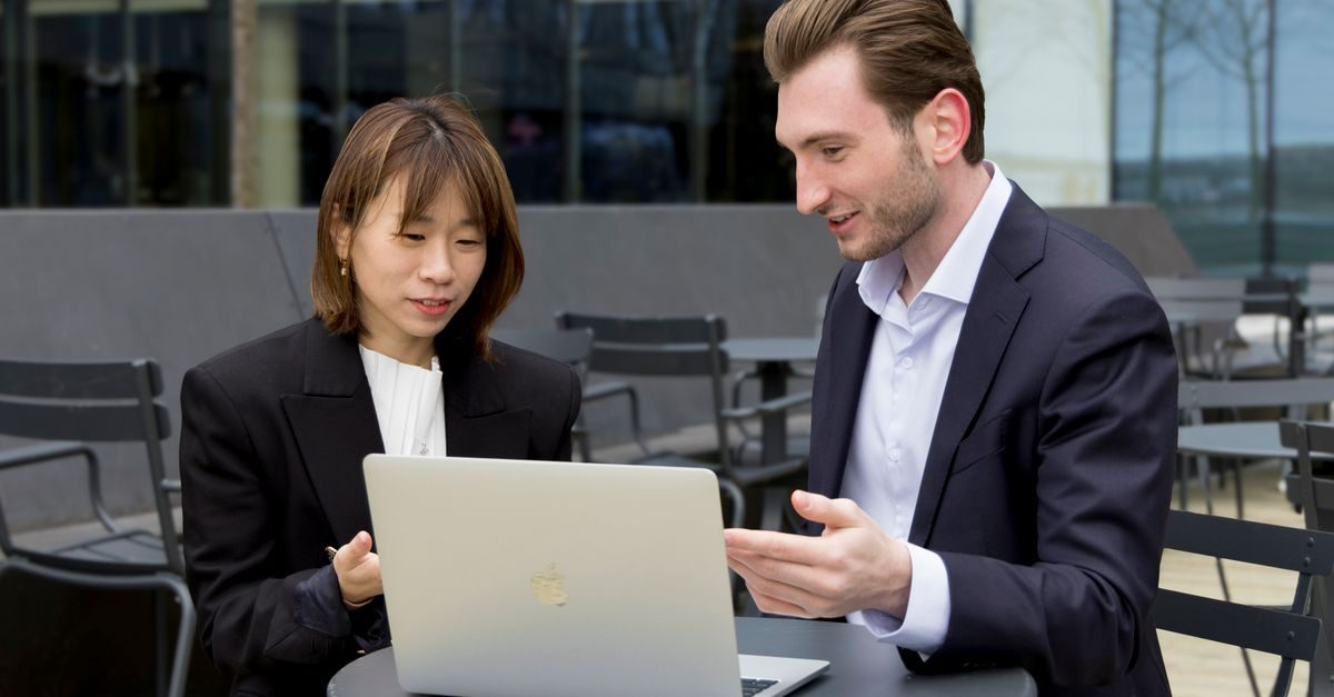 Two professionals collaborating over a laptop during an outdoor business meeting